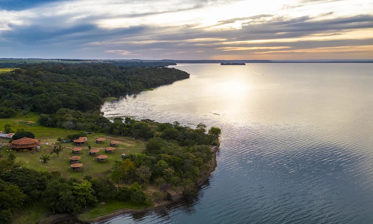 Vista aérea do pôr do sol no Rio Grande, com ranchos à beira-rio na região Maravilhas do Rio Grande
